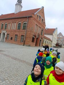 Grupa dzieci stojąca parami przy Starym Ratuszu na olsztyńskiej starówce
