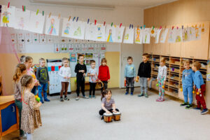 Grupa dzieci grająca na instrumentach muzycznych (grzechotki, klawesy, tamburyna, trójkąty, bongosy)