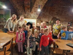 Grupa dzieci wraz z nauczycielkami w piwnicy olsztyńskiego zamku