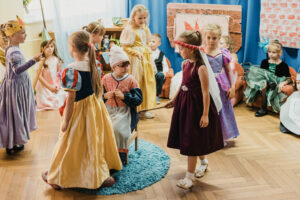 Dzieci wcielający się w rolę bohaterów z bajki Kopciuszek podczas tańca wokół kopciuszka