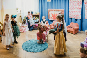 Dzieci wcielający się w rolę bohaterów z bajki Kopciuszek podczas mierzenia bucika przez siostre