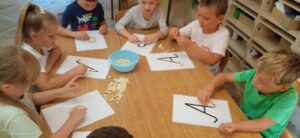 Dzieci układające fasolki na konturze litery A