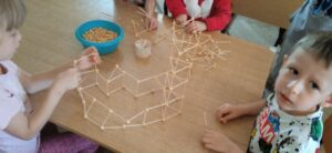 Grupa dzieci tworzy konstrukcję z wykałaczek.