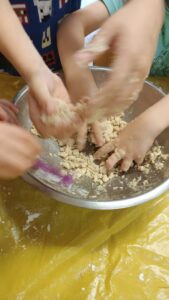 Ręce dzieci ugniatające piasek kinetyczny w misce