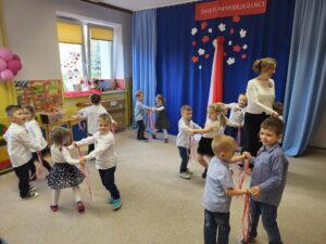 grupa dzieci tańcząca w parach oraz nauczycielka tańcząca razem z nimi