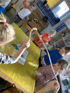 grupa dzieci malująca farbami na pomocą sznurka