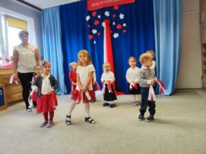 grupa dzieci tańcząca z biało czerwonymi wstążeczkami