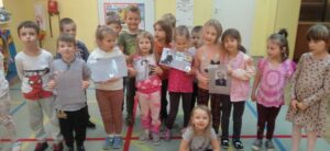 Grupa dzieci trzymających fotografie przedstawiające zdjęcia i informacje o Marii Zientarze-Malewskiej.