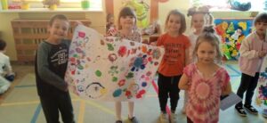 Dzieci trzymające arkusz papieru z namalowanymi kwiatami.