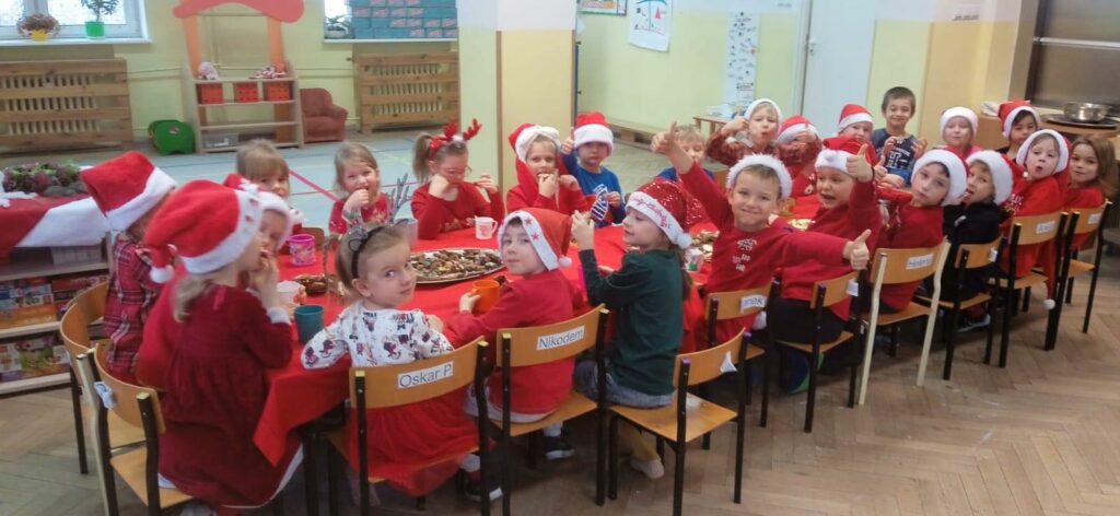 grupa dzieci siedząca przy stole podczas imprezy z okazji imienin św. Mikołaja