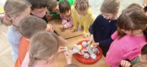Grupa dzieci odwija jaja z folii aluminiowej.