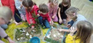 Grupa dzieci tworzy makietę Parku Jurajskiego.