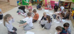 Grupa dzieci mierzy figurki dinozaurów.