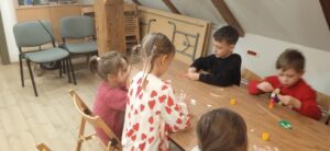 Dzieci przy stoliku wykonują prace plastyczne.