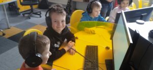 grupa dzieci w słuchawkach przed komputerami