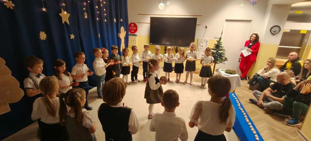 Grupa dzieci w strojach galowych podczas występu artystycznego.