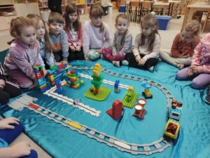 Dzieci siedzące przy makiecie wioski św. Mikołaja skonstruowanej z klocków LEGO.