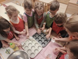 Dzieci wkładające papilotki do formy.