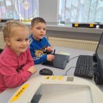Chłopiec i dziewczynka wykonują zadanie w komputerze.