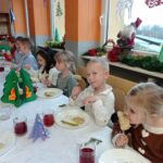 zastawione świątecznie stoły, dzieci jedzą obiad