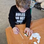 Chłopiec przykładający iglaka do ozdoby z masy porcelanowej