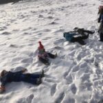grupa dzieci leży na śniegu