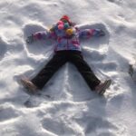 dziecko leży na śniegi u robi aniołka
