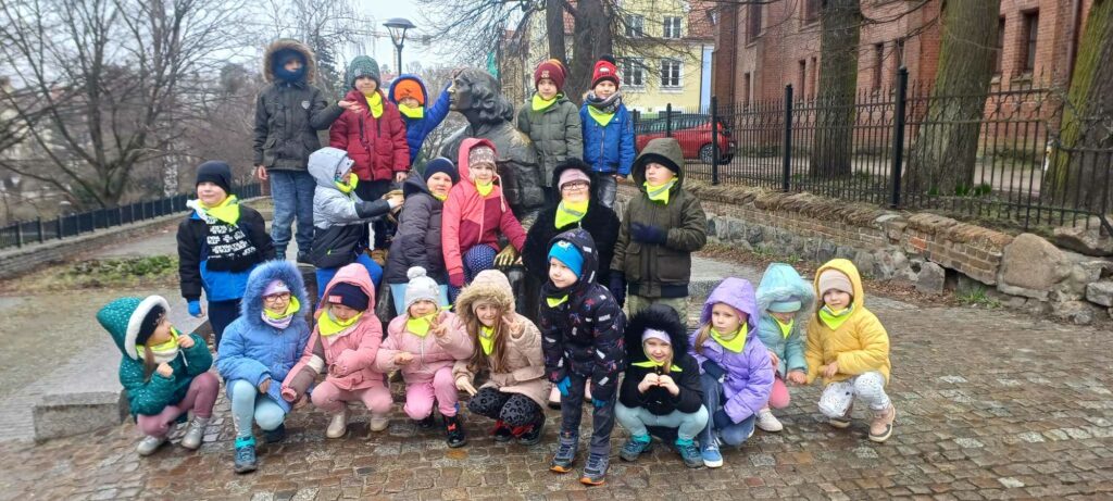 dzieci stoją przy pomniku Mikołaja Kopernika