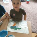 chłopiec maluje farbami po foli aluminiowej