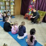 Dzieci słuchają czytanej książki w bibliotece