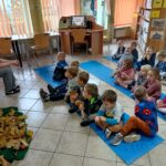 Dzieci siedzą na niebieskich matach w bibliotece