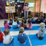 Dzieci słuchają bajki czytanej przez panią w bibliotece