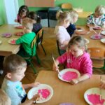 Dzieci malują papierowe talerze na różowo