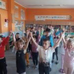 grupa dzieci stoi i podnosi ręce