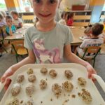 Dziewczynka pokazuje kulki z suszonych owoców i orzechów.