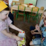 Dziewczynka częstuje dzieci cukierkami
