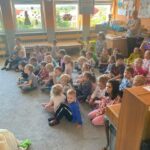 Dzieci siedzą na dywanie i oglądają przedstawienie
