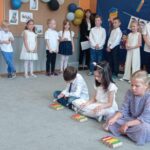 troje dzieci gra na dzwonkach, z tyłu grupa dzieci