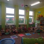 grupa dzieci siedzi w sali, na dywanie rzeczy do ćwiczeń