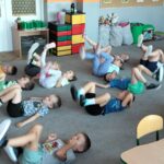 Dzieci leżą na dywanie i robią rowerek