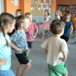 Dzieci idą po dywanie z rękoma na biodrach