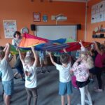 grupa dzieci bawi się chustą animacyjną