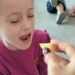 Dziewczynka z zamkniętymi oczami próbuje kawałek jabłka