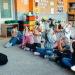 Dzieci siedzą na dywanie i uczą się ochraniać głowę