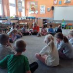 grupa dzieci w kole, dzieci słuchają czytania biblii
