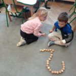 dwoje dzieci przed nimi cyfra 2 ułożona z klocków