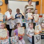 Grupa dzieci z dorosłym podczas wręczenia nagród konkursowych.