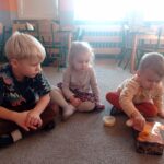 troje dzieci na dywanie, chłopiec ma w ręku łyżkę