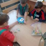 troje dzieci przyczepia osiem klamerek do krążka