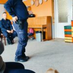 Policjant pokazuje dzieciom, w którym miejscu trzyma broń